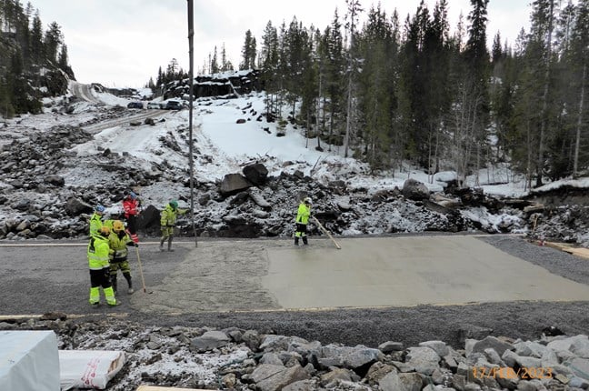 Bildet viser arbeidsfolk som støper bunnen i kulverten ved Finnsåselva. Kulvert er et stort firkantet rør i betong. Foto Statens vegvesen.