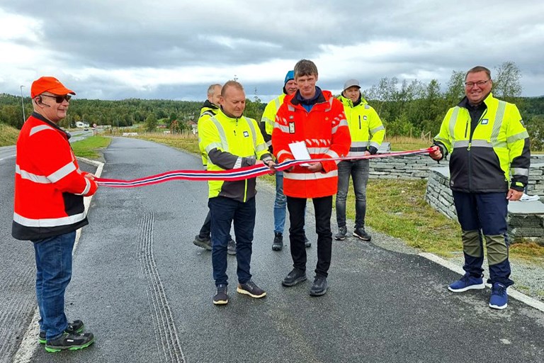 Representanter fra Statens vegvesen og Anlegg Nord møtes ved en veg og klipper snor for å markere starten på ny driftskontrakt. 