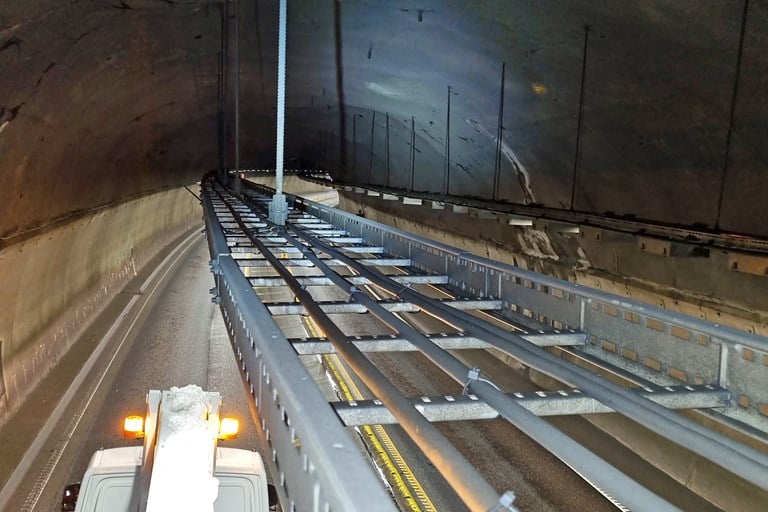 Bilde av kabelbru i tunnel og dens feste i tunneltaket. Under kjører et vogntog.