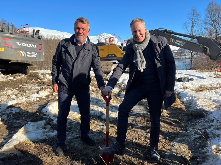Bildet viser ordfører i Tromsø Gunnar Wilhelmsen og Samferdselsminister Jon-Ivar Nygård, stående side om side, med én hånd hver på en spade som står mellom dem.  
