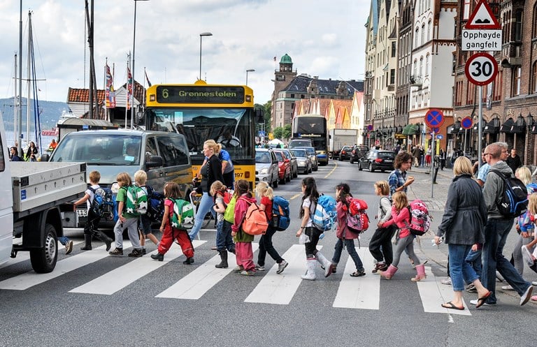 Barn går over fotgjengerfelt i trafikkert gate
