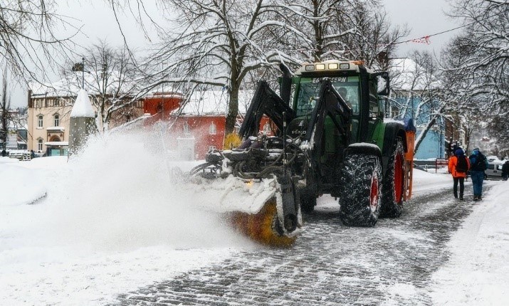 Figur 30a er et bilde av en traktor med roterende kost som koster bort snø.