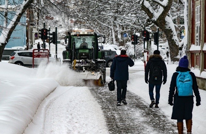 Figur 30b er et foto av en traktor med roterende kost som koster bort snø.