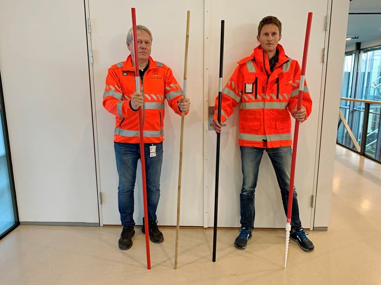 Øystein Larsen og Bård Nonstad viser fram brøytestikker, og noen av disse typene blir med i testen i vinter. Fra venstre: rødmalt furu, bambus, svartmalt furu, rød plast skrubrøytestikke.