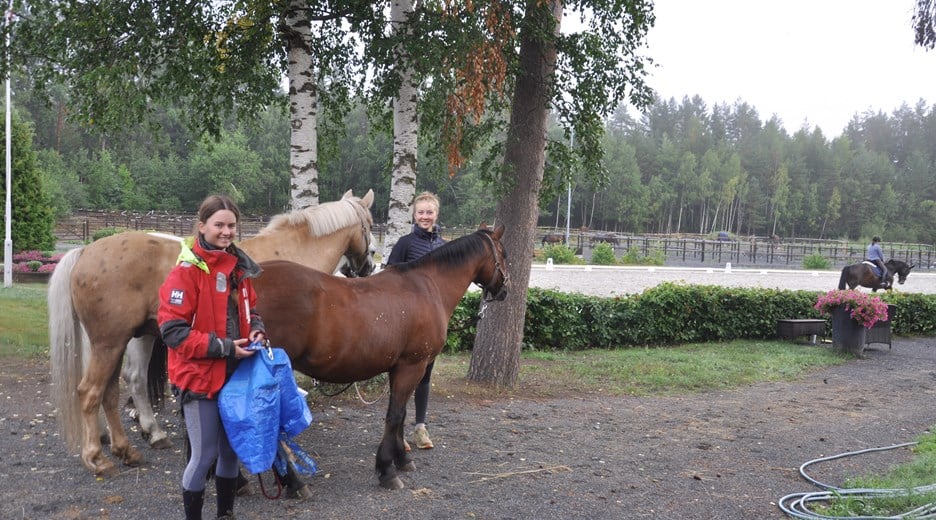 to jenter med hester på ridesenter
